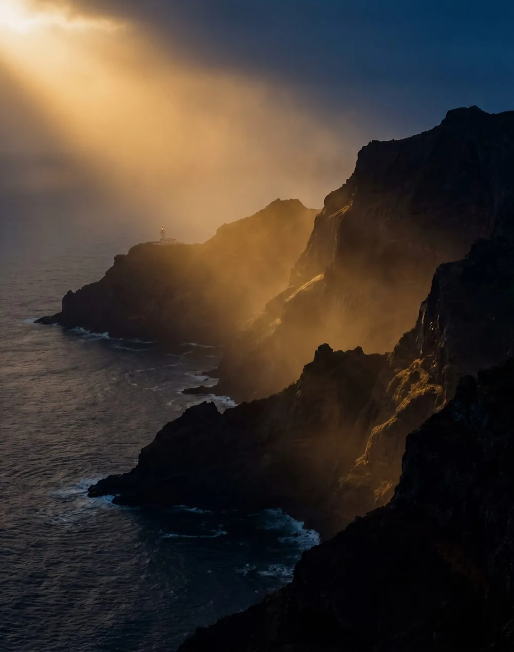 Falésias da costa norte da Madeira ao anoitecer, iluminadas por um feixe de luz dourada